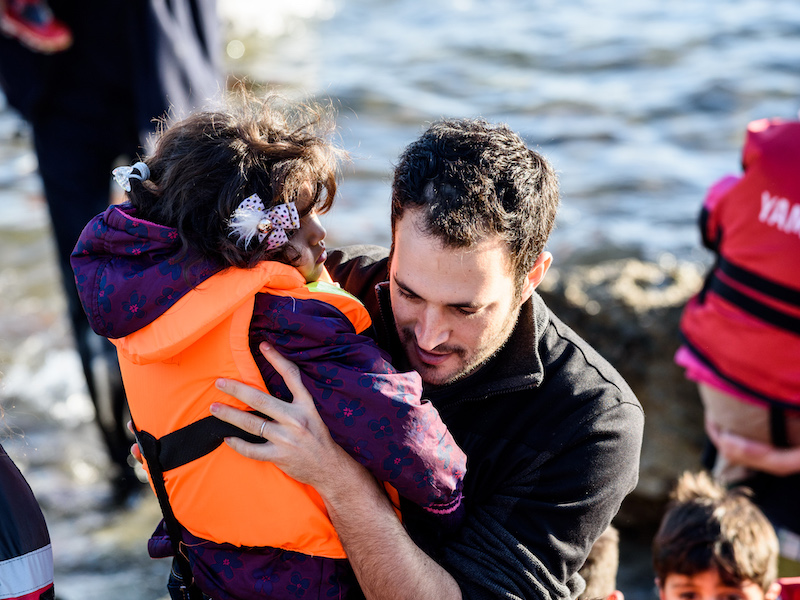 Yotam Polizer aids a refugee in Lesbos, Greece in 2015.